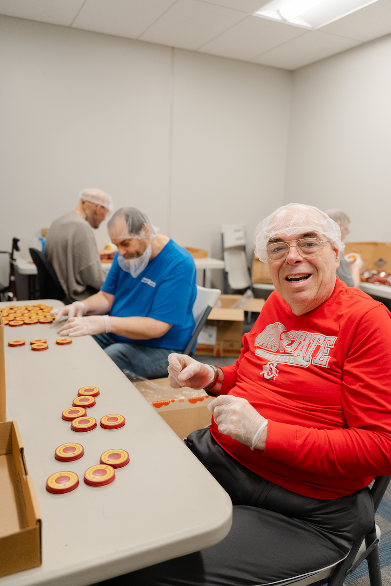 Individual in a red shirt stocking a high shelf