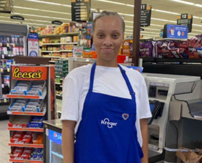 Angel wearing a blue apron while working at Kroger