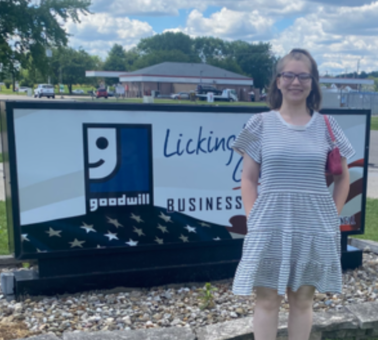 Patience standing in front of a Goodwill sign