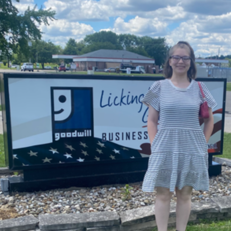 Patience standing in front of a Goodwill sign